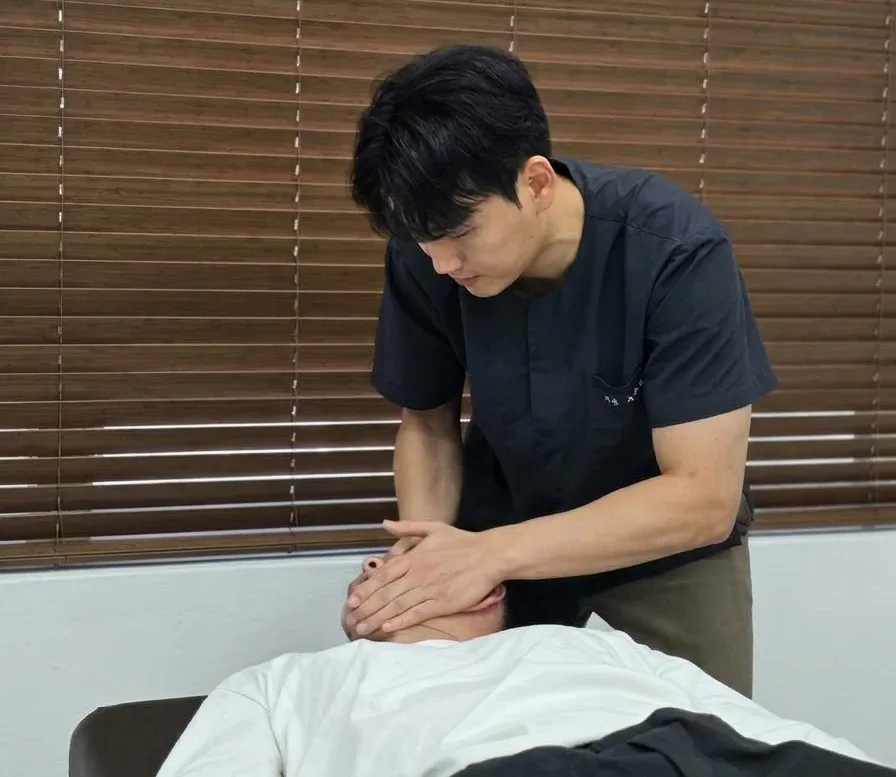 원장이 환자의 목을 추나 요법으로 치료하는 모습